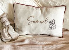 a teddy bear sitting on top of a bed next to a pillow that says samuel