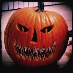 a carved pumpkin with sharp teeth on it's face