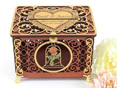 an ornate wooden box with a rose and heart on it, next to some flowers