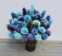 a vase filled with blue and purple flowers sitting on top of a wooden table next to a white wall