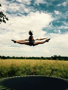 a woman flying through the air while riding on top of a trampoline in a field