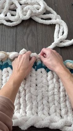 a woman is working on a rug with white yarn and crochet hooks attached to it