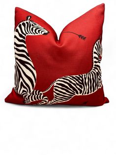 a red pillow with two zebras on it's sides and one is facing the opposite direction