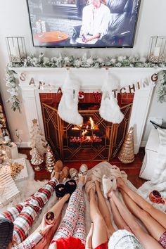 people laying on the floor in front of a fireplace with stockings and stockings hanging from it