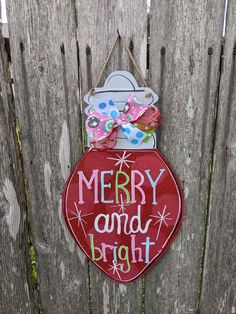 a merry and bright sign hanging on the side of a wooden fence with a bow