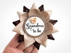 a hand holding a brooch that says grandma to be with a teddy bear on it