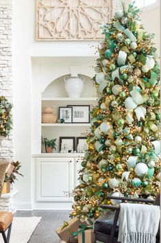 a living room decorated for christmas with green and gold ornaments on the tree, fireplace mantel