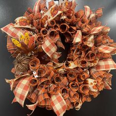 an orange and white wreath with autumn decorations