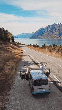 two people standing on the back of a pick up truck with their arms in the air