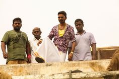 three men standing next to each other on top of a wooden structure with one man holding a white cloth