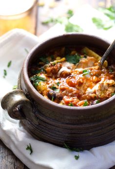 a wooden bowl filled with food on top of a white cloth next to a spoon