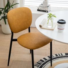 a white table with two chairs and a potted plant