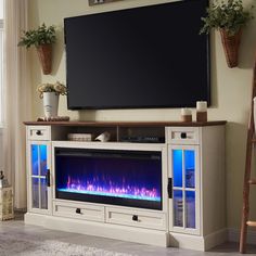 an entertainment center with a television and fire place in front of the tv on top of it