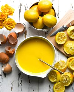 a bowl of yellow liquid next to sliced lemons and eggs