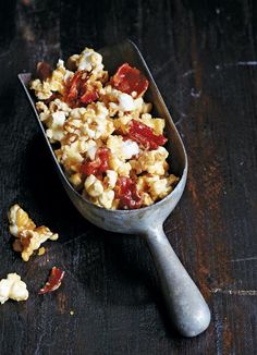 a metal scoop filled with popcorn sitting on top of a wooden table