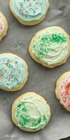 four decorated cookies sitting on top of a piece of paper with sprinkles