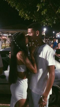 a man and woman kissing in front of a car