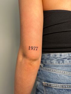 a woman with a small tattoo on her left arm and the number 1971 written in black ink