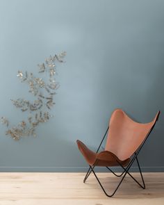 a chair sitting on top of a hard wood floor next to a wall with a metal sculpture