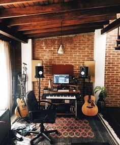 a living room filled with musical equipment next to a brick wall and floor covered in rugs