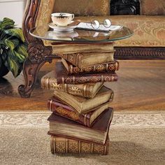 a stack of books sitting on top of a glass table next to a couch in a living room