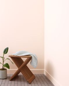 a wooden chair sitting next to a potted plant on top of a tiled floor