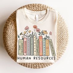 a t - shirt that says social worker with books and flowers on it in front of a wicker basket