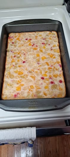 a square cake pan with fruit toppings on top of an oven burner, ready to be baked