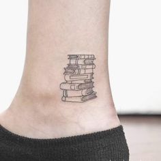 a small tattoo on the ankle of a woman's foot with books stacked up