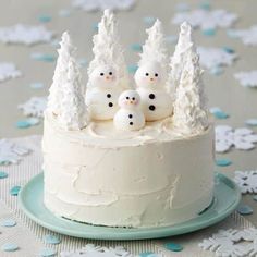 a frosted cake decorated with snowmen and trees