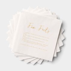 five white napkins with gold foil lettering on them