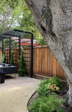 a backyard with a tree, patio furniture and fenced in area next to it