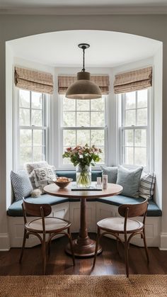 a kitchen table with two chairs and a bench in front of the bay window,