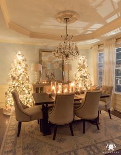 the dining room is decorated for christmas with white trees and candles on the table in front of it