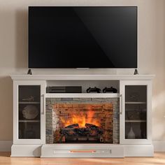 a flat screen tv mounted on top of a white entertainment center next to a fire place