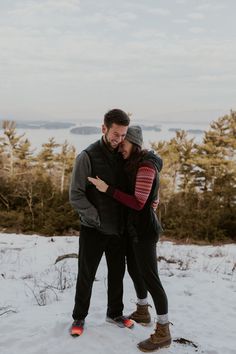 a man and woman standing in the snow with their arms around each other as they kiss