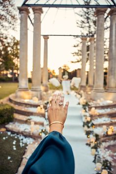 a woman's hand with two wedding rings on her finger in front of an outdoor ceremony