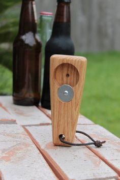 a wooden speaker sitting on top of a table next to two beer bottles and a bottle opener