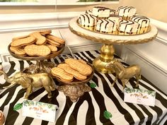 a table topped with cookies and desserts on top of a zebra print table cloth