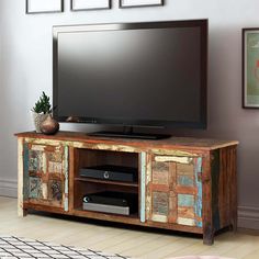 a flat screen tv sitting on top of a wooden entertainment center in a living room