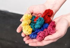 two hands holding multicolored balls of yarn