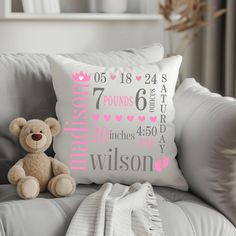 a teddy bear sitting on top of a gray couch next to a pillow with pink lettering