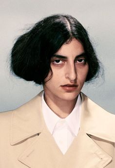 a woman with black hair and a trench coat