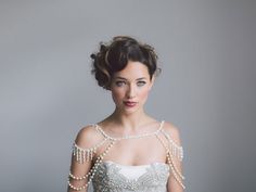 a woman in a wedding dress with pearls on her shoulder