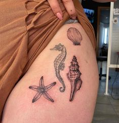 a woman's thigh with seahorse, starfish and seashell tattoos on it