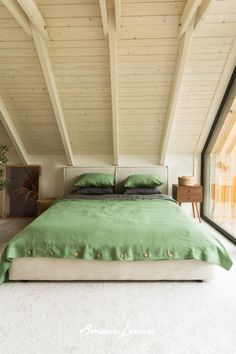 a bed with green sheets and pillows in a room