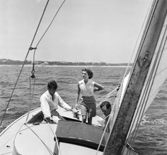 two men and a woman on a sailboat in the water