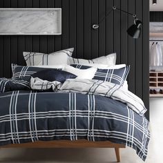 a bed with black and white plaid comforter in a dark room next to a lamp