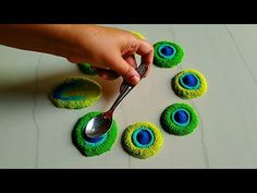 a person holding a spoon in front of some green and blue decorations on a table