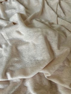 an unmade bed with white sheets and pillows